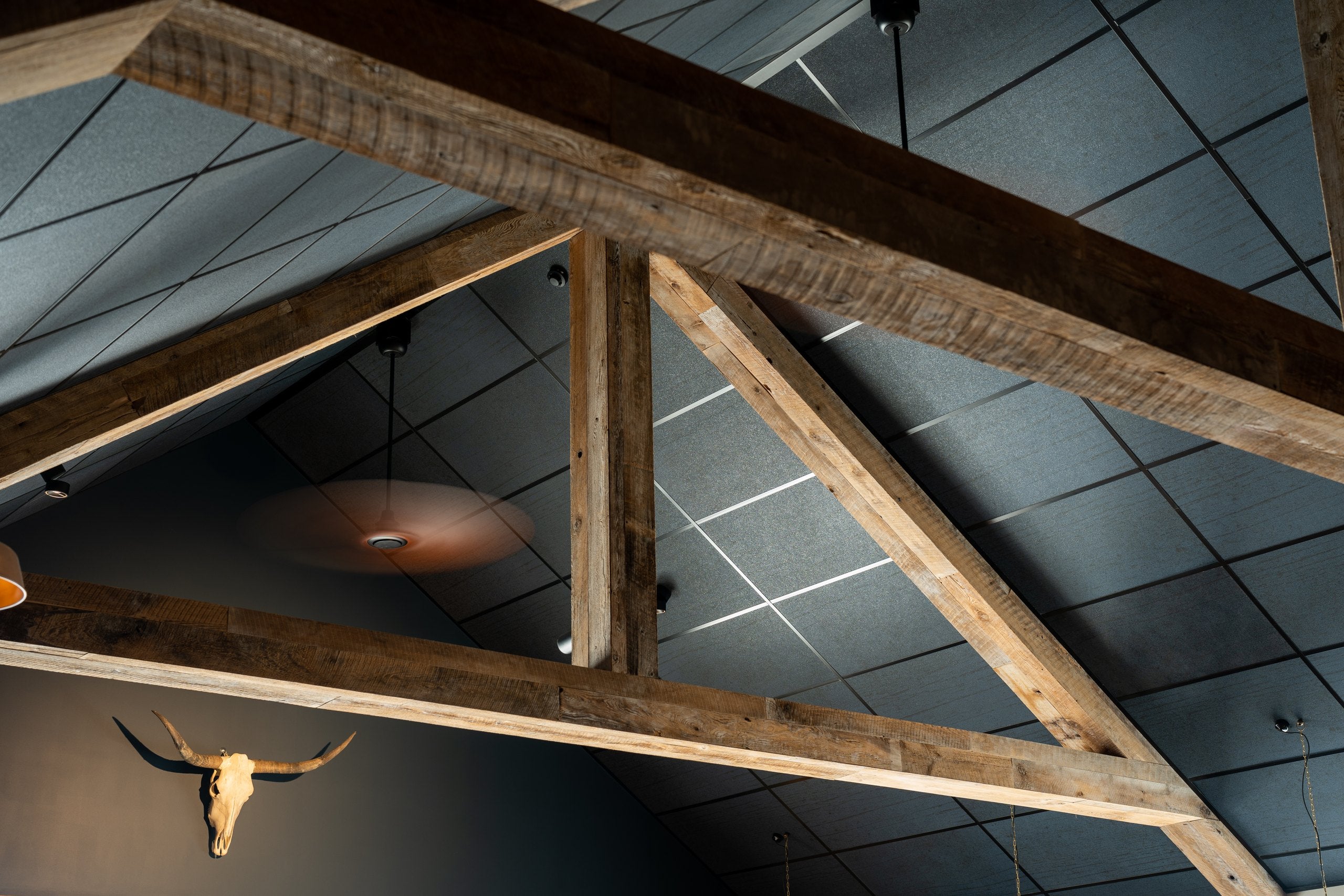 Charcoal acoustic ceiling tiles in a suspended grid between exposed timber trusses, T&R Interior Systems installation at Lone Star